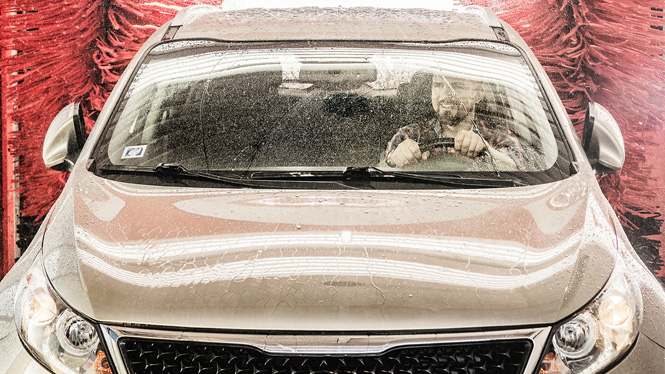 mand sidder i bil, mens den bliver vasket
